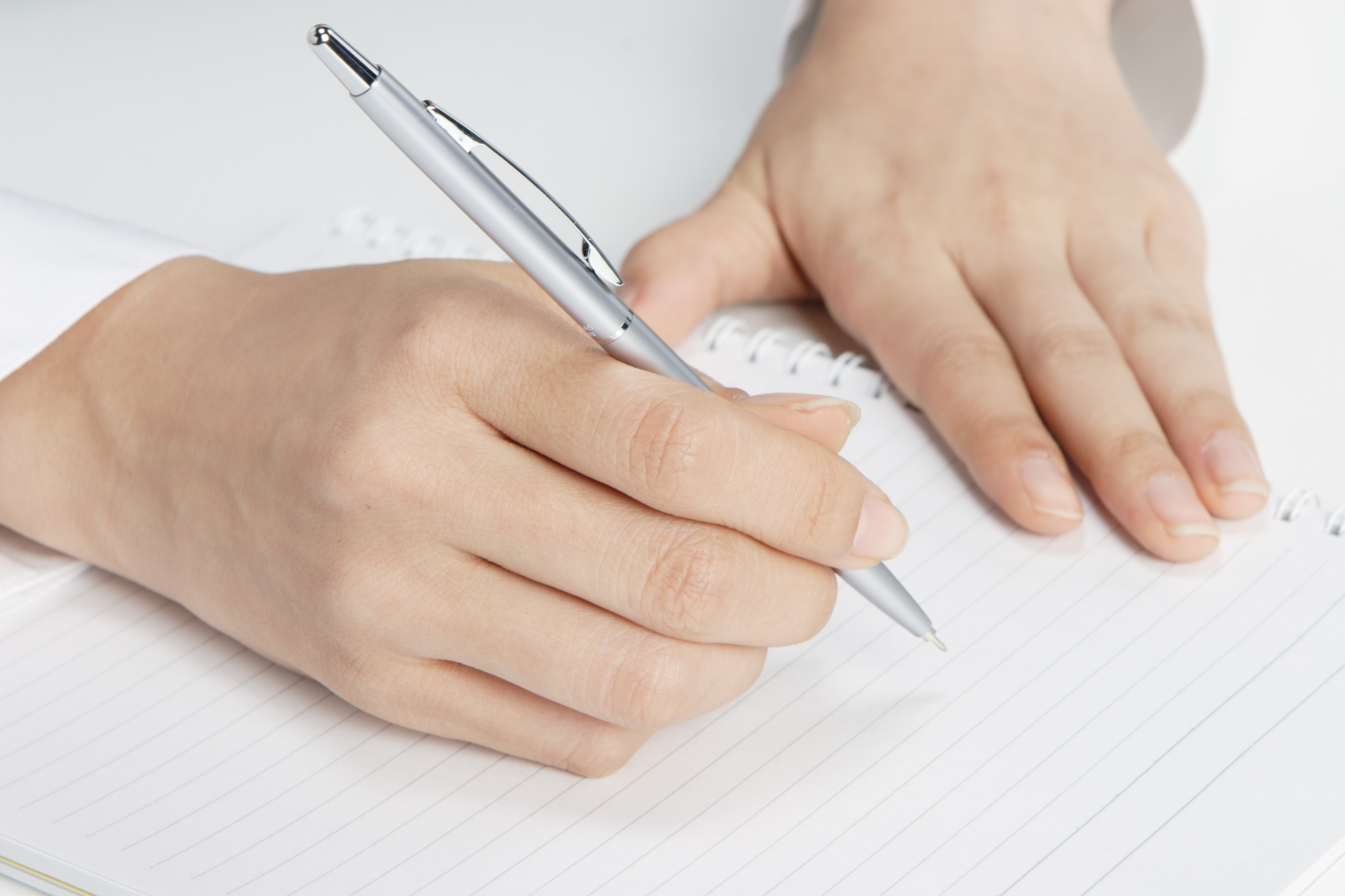 ノートにペンで書こうとしている、手元アップの写真