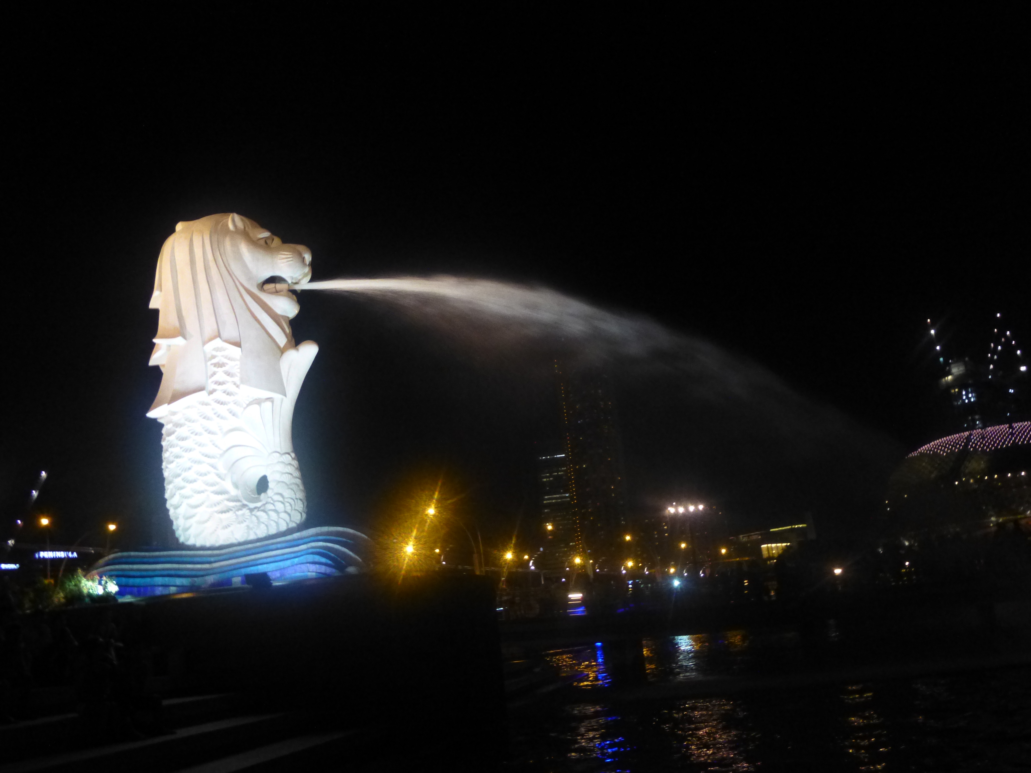 夜のシンガポールでマーライオンが水を吹いている写真